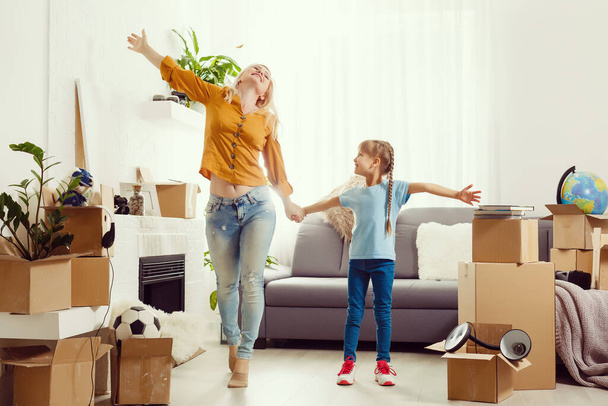 Muito jovem mãe e sua filhinha fofa se divertindo em novo apartamento e desempacotando caixas móveis - Foto, Imagem