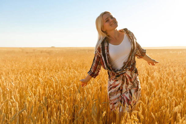 A girl in the midst of wheat spikelets. Caucasian woman posing with spikelets outside. - Photo, Image