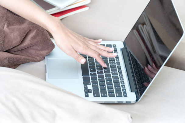 Focus hand of young woman typing on keyboard sitting on couch in the bedroom.Lifestyle concept - 写真・画像