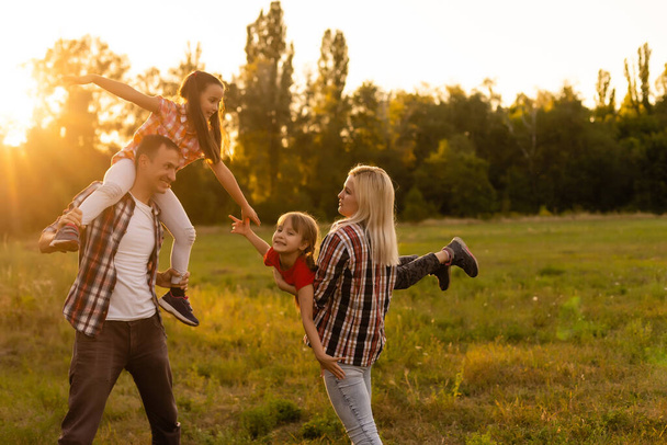 Ευτυχισμένη οικογένεια στο ηλιοβασίλεμα στη φύση - Φωτογραφία, εικόνα