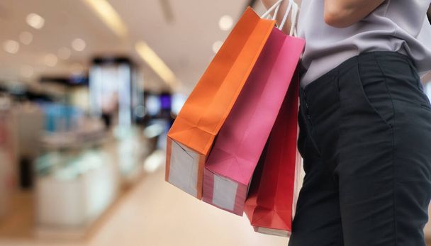 Hand einer Frau mit Einkaufstaschen über dem Hintergrund von Einkaufszentren. Glück, Konsum, Verkauf und Menschenkonzept. - Foto, Bild