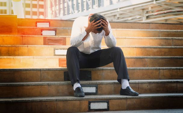 Concept business people failure and unemployment problem. Business men bankruptcy and debt sitting on the stairs with hands close his head. Unemployed businessman frustrated and desperate to find work. - Photo, Image