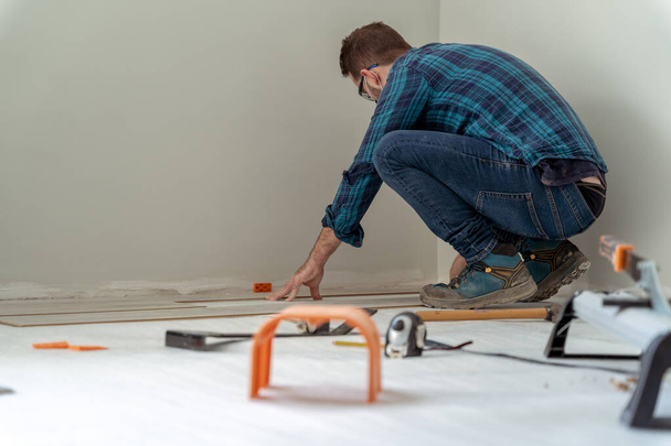Carpenter worker installing laminate flooring in the room. - Fotografie, Obrázek