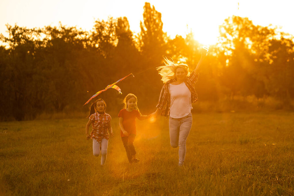 凧を持って夕暮れ時に畑の母親と娘たちは - 写真・画像