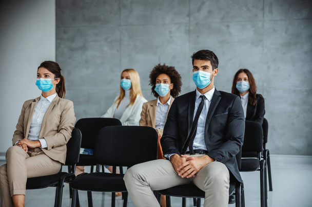 Small group of multicultural group of business people with face masks sitting on seminar during corona virus. - Фото, изображение