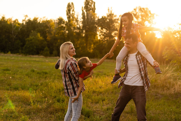 Ευτυχισμένη οικογένεια: μητέρα πατέρας και παιδί κόρη στη φύση στο ηλιοβασίλεμα - Φωτογραφία, εικόνα