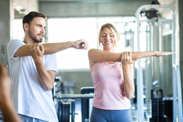 Couple sportif étirant le muscle avant l'activité sportive dans le club de gym fitness exercice heureux ensemble - Photo, image