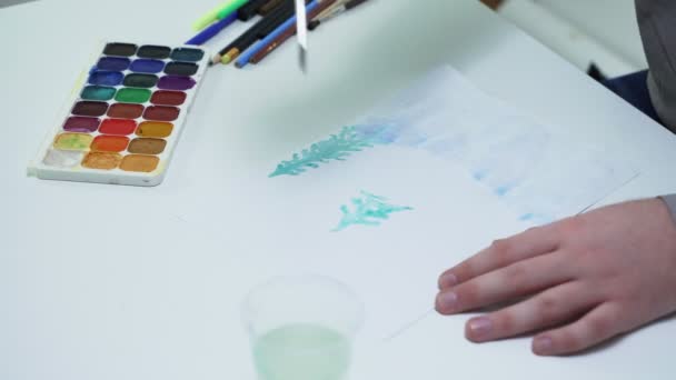 Primo piano di artista disegna con acquerelli su una carta bianca al tavolo in uno studio bianco - Filmati, video