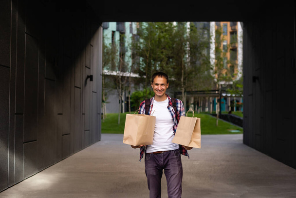 entrega, correo y concepto de personas - hombre feliz entrega de alimentos en bolsa de papel desechable a casa del cliente - Foto, imagen