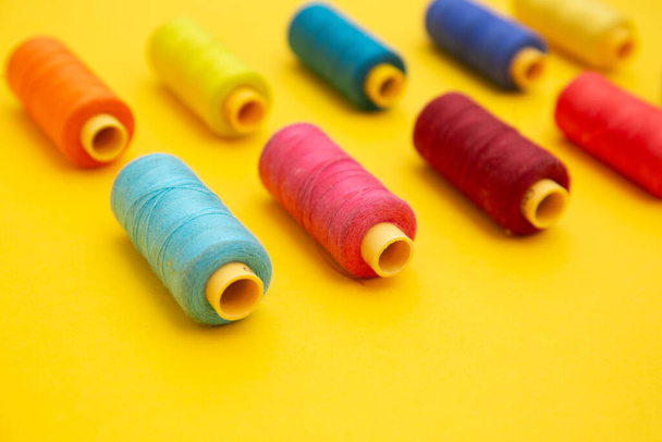 vista superior de bobinas de hilo de colores sobre fondo amarillo, costura, lugar para el texto - Foto, imagen