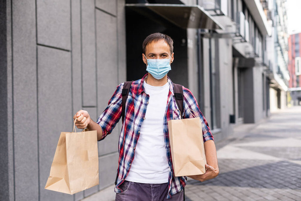 Delivery man holding paper bag with food, food delivery man in protective mask - Foto, afbeelding
