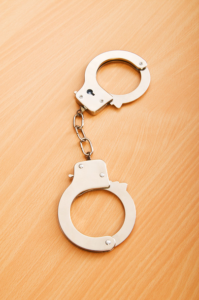 Металлические наручники на деревянном фоне
 - Фото, изображение