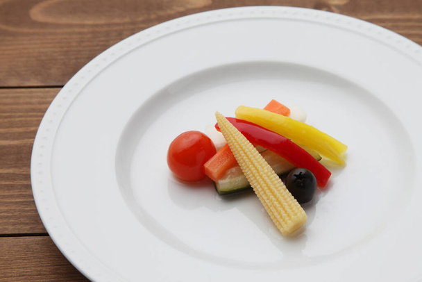 маринованные огурцы салат овощей на тарелке изолированы на деревянный стол - Фото, изображение