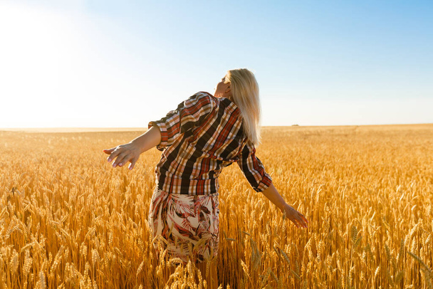 Woman in a wheat field on the background of the setting sun - Фото, изображение