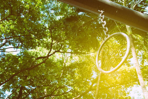 Старые металлические гимнастические кольца в общественном парке с утечкой света. - Фото, изображение
