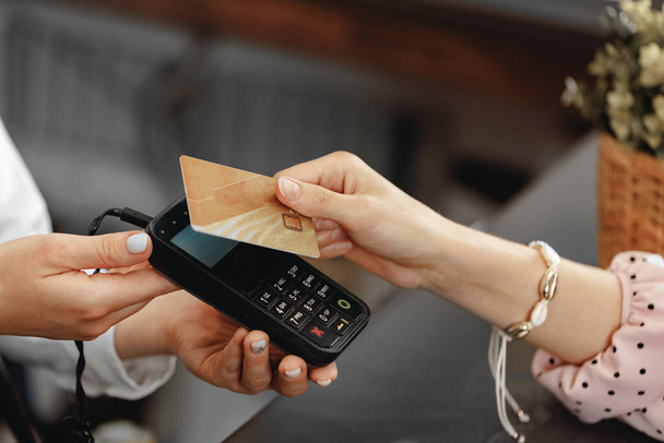 Close up of hand of customer paying with contactless credit card - 写真・画像