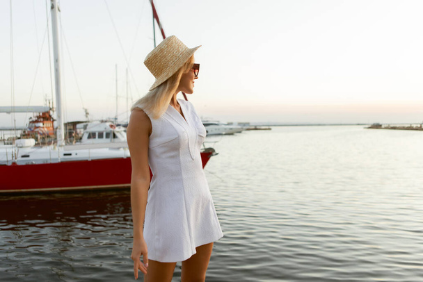 Sommerporträt einer jungen, fröhlichen blonden Frau mit Hut und Sonnenbrille auf See - Foto, Bild