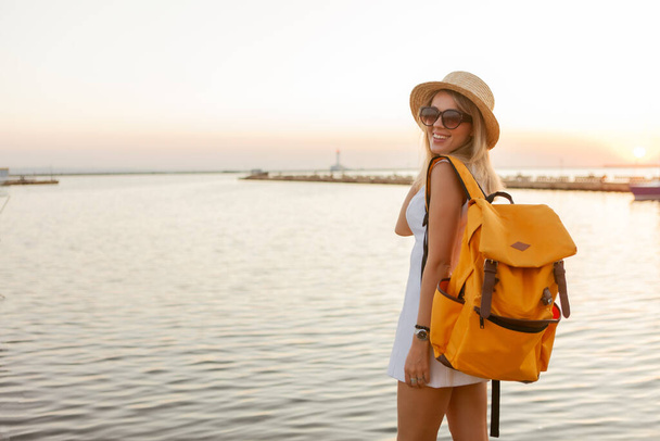 Портрет молодой женщины-туристки с большим рюкзаком на восходе солнца в море. Концепция путешествия и туризма - Фото, изображение