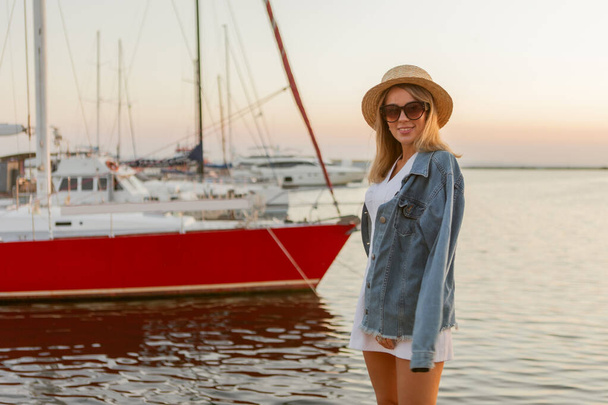 Summer portrait of young cheerful blonde woman in hat and sunglasses at sea - Photo, Image