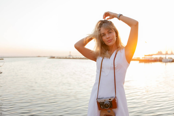 Veselá a veselá atraktivní blondýnka při východu slunce na pláži. Koncept cestování a volného času - Fotografie, Obrázek