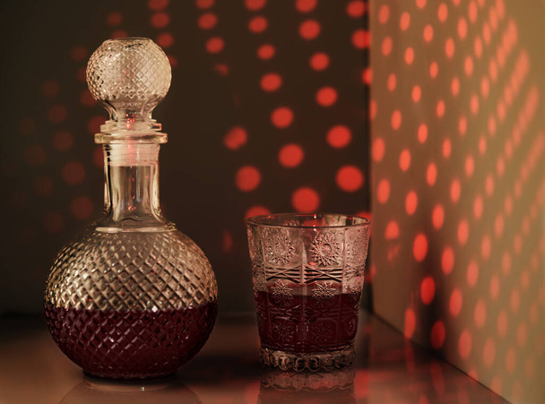 壁にパターンの形で珍しい照明と赤ワインとワインのガラスのジャグ - 写真・画像