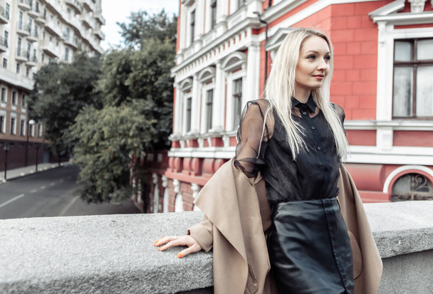 Linda mujer de moda atractiva en abrigo de otoño posando sobre el fondo de la arquitectura urbana. Moda callejera - Foto, Imagen