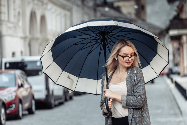 Blond business woman with umbrella in urban street. Waiting for the rain - Zdjęcie, obraz