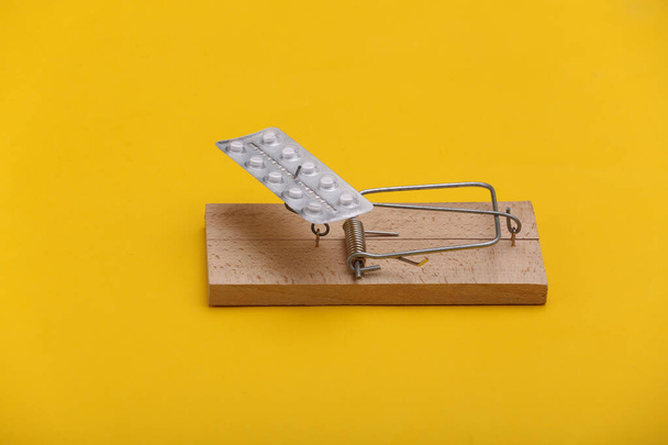 Mousetrap with blister of pills on yellow background. Health and business concept - Photo, Image