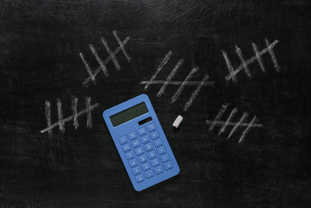 Nombre de comptage de craie marque sur le tableau noir de la salle de classe avec calculatrice - Photo, image