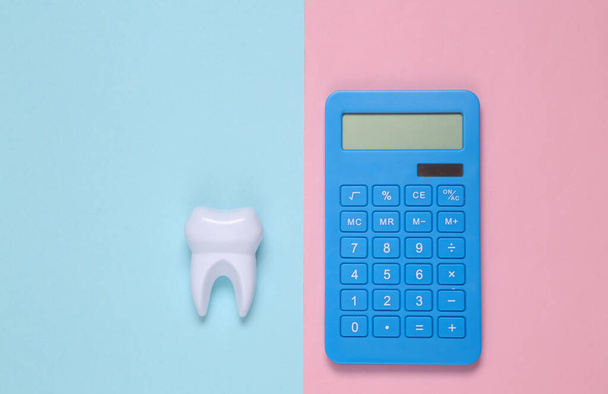 Diente falso sobre fondo rosa azul. Costes del tratamiento dental. Vista superior - Foto, imagen