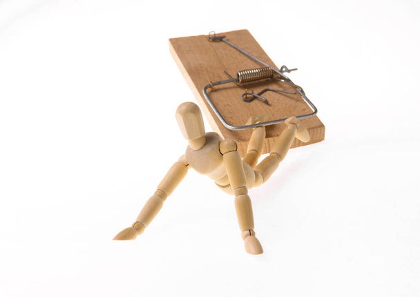 Marionnette en bois prise dans un piège à souris isolé sur fond blanc. tromperie, fraude, piège - Photo, image