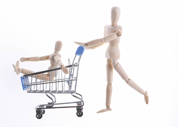 Shopping concept. Wooden puppets with supermarket trolley isolated on white background - Φωτογραφία, εικόνα
