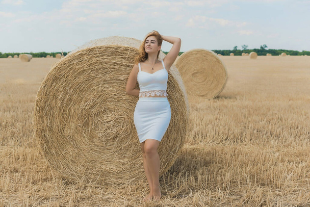 Mujer natural moderna de talla grande con caderas llenas, bonita figura en traje blanco en el campo. Concepto de feminidad - Foto, imagen