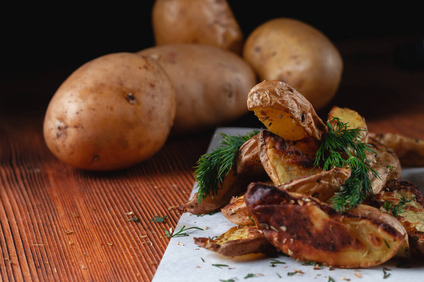 Deliziose patate di campagna al forno con spezie, aneto e cipolle verdi, su un tavolo di legno - Foto, immagini