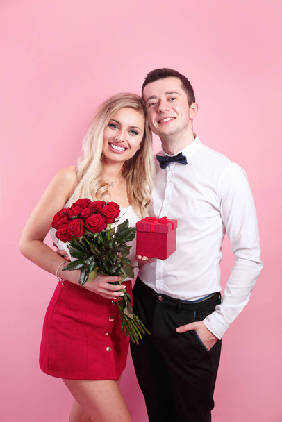 Valentines day. Handsome elegant boy is proposing to his beautiful girlfriend with her roses and smiling. - Фото, зображення