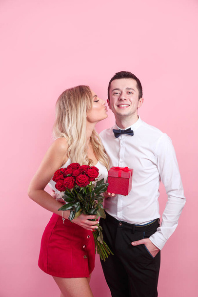 Valentines day. Handsome elegant boy is proposing to his beautiful girlfriend with her roses and smiling. - Fotó, kép