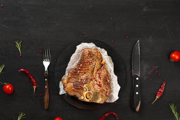 Top view of grilled t-bone steak on black table - Foto, Imagem
