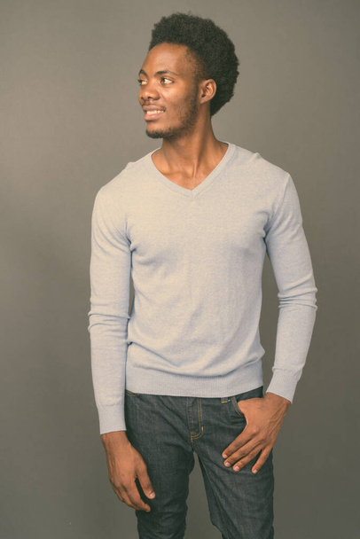 Young handsome African man against gray background - 写真・画像