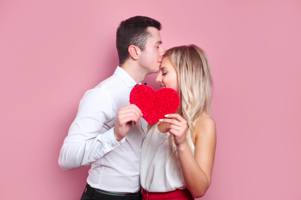 Valentines day. Young couple holding red love heart and kissing. Couple in love - Foto, afbeelding