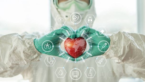 Tecnología médica, tecnología de la salud global y concepto del día mundial de la salud del corazón con el médico cardiólogo en ppe para la protección covid-19 que sostiene el corazón en el laboratorio cardíaco del hospital para la investigación científica de laboratorio - Foto, imagen
