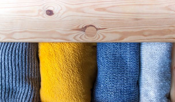 Tiroir commode en bois ouvert avec des vêtements chauds en laine tricotée. Stockage vertical à domicile. Organisation de garde-robe. Couleurs tendance. - Photo, image