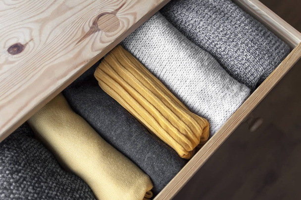 Open wooden dresser drawer with warm knitted woolen clothes. Home vertical storage. Wardrobe organisation. Trendy colors. - Photo, Image