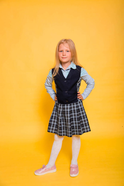 Girl in school uniform posing isolated on yellow background. - Φωτογραφία, εικόνα
