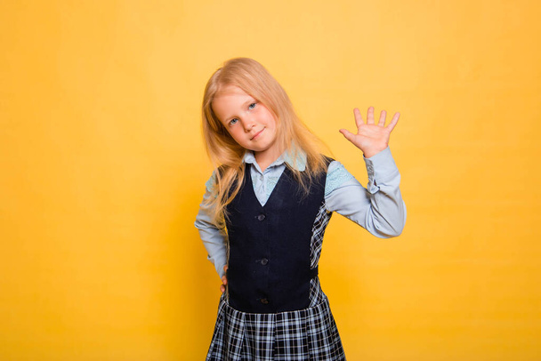 Girl in school uniform posing isolated on yellow background. - Φωτογραφία, εικόνα