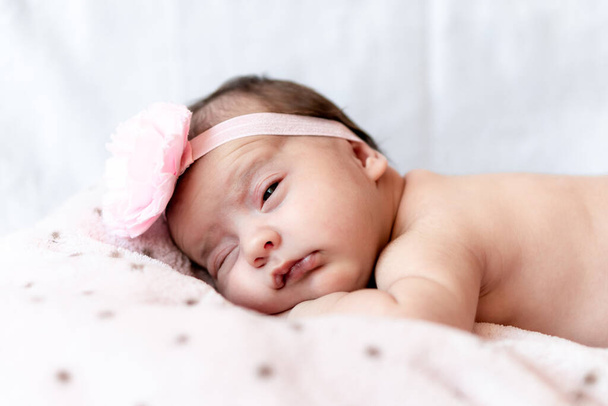 Childhood, care, motherhood, health, medicine, pediatrics concepts - Close up Little peace calm naked infant newborn baby girl in pink hat sleeps resting take deep nap laying on tummy on soft bed - Photo, Image