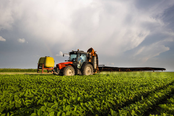 春には散布機で大豆畑に農薬を散布するトラクター - 写真・画像