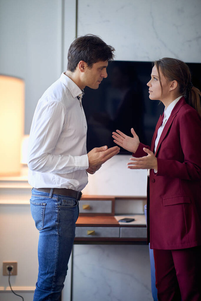 Young couple arguing at the hotel room at their business trip for new deal. Hotel, business, people - Photo, image