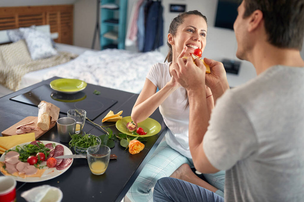 A young couple having fun while having a breakfast in a cheerful atmosphere at home. Couple, home, breakfast, togetherness - 写真・画像