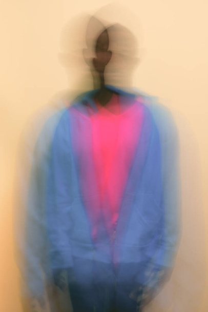 Estudio de un joven africano con chaqueta azul y camisa rosa sobre fondo blanco - Foto, imagen