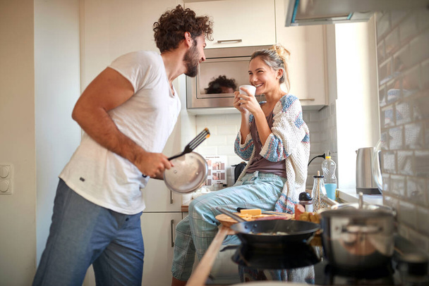 A young couple in love having good time while preparing a breakfast together on a beautiful morning. Cooking, together, kitchen, relationship - Valokuva, kuva
